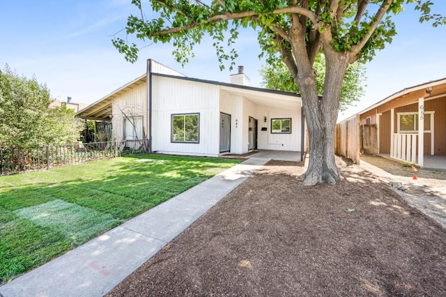 view of front facade with fence, a chimney, an attached carport, and a front yard