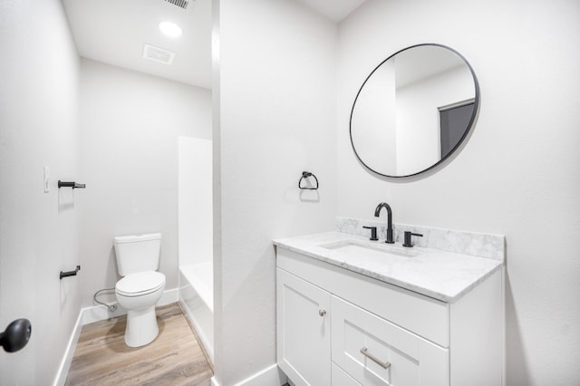 bathroom featuring toilet, baseboards, visible vents, wood finished floors, and vanity