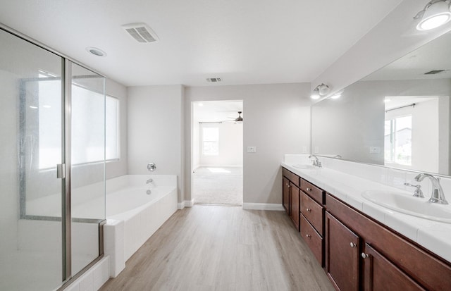 full bathroom with wood finished floors, a sink, a bath, double vanity, and visible vents