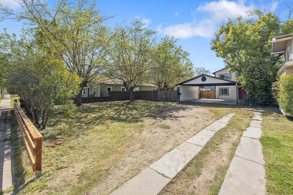 1331 N Roosevelt Ave, Fresno, CA 93728 - view of front of house with dirt driveway, fence, and a carport