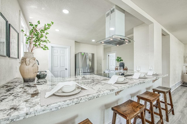 2225 N Van Ness Blvd, Fresno, CA 93704 - kitchen with freestanding refrigerator, island range hood, a textured ceiling, black electric cooktop, and wood finished floors
