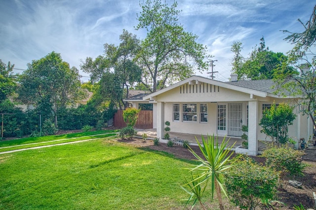 view of front of home featuring stucco siding, a front yard, and fence