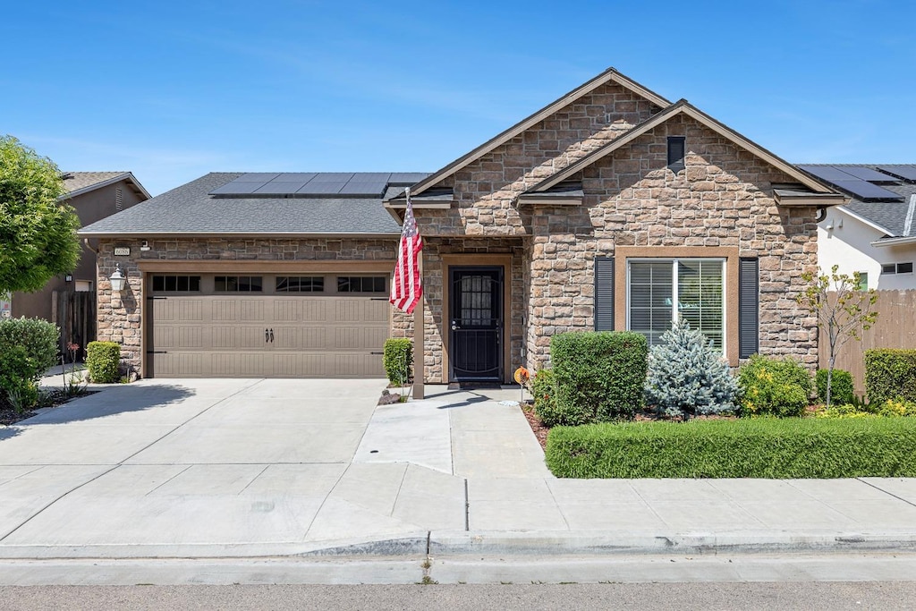 6086 E Fedora Ave, Fresno, CA 93727 - view of front facade featuring stone siding, solar panels, driveway, and an attached garage