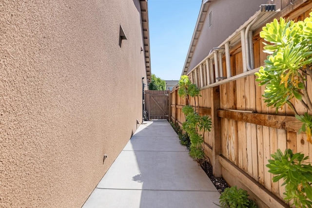 view of home's exterior with stucco siding, fence, and a gate