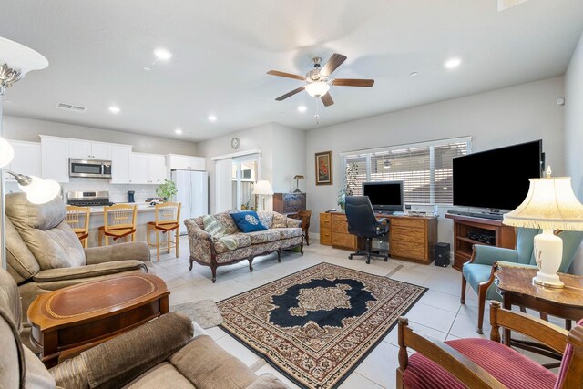 living room featuring light tile patterned floors, visible vents, ceiling fan, and plenty of natural light