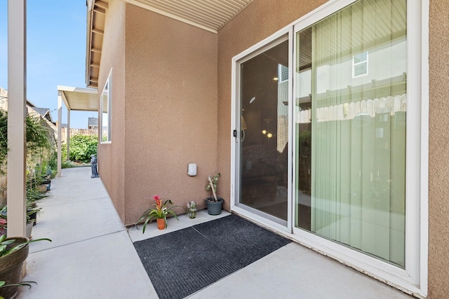 property entrance with stucco siding and a patio