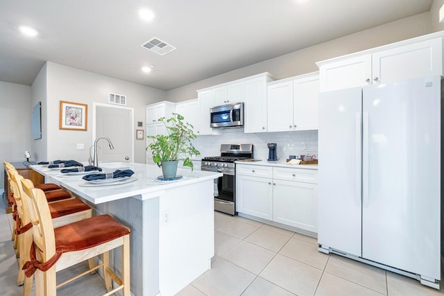 kitchen with appliances with stainless steel finishes, light tile patterned floors, visible vents, and white cabinetry