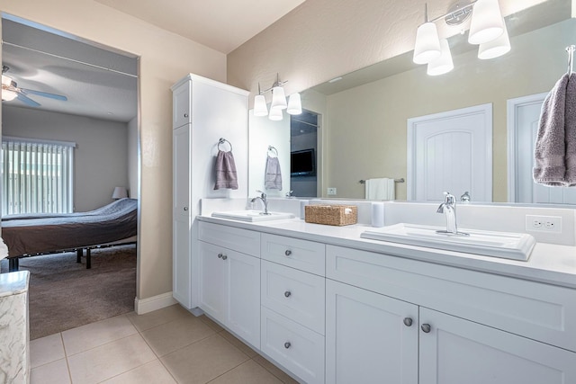 ensuite bathroom with double vanity, a sink, a ceiling fan, and tile patterned floors