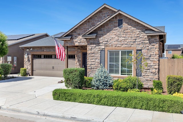 view of front of home with stone siding, fence, concrete driveway, and a garage