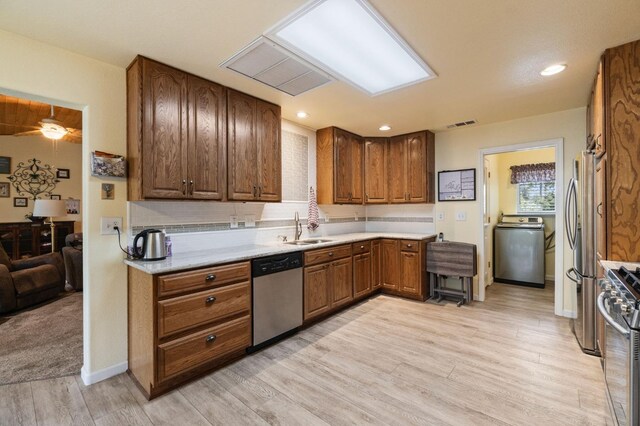 43443 Running Deer Dr, Coarsegold, CA 93614 - kitchen with light wood-style flooring, washer / clothes dryer, a sink, stainless steel appliances, and backsplash