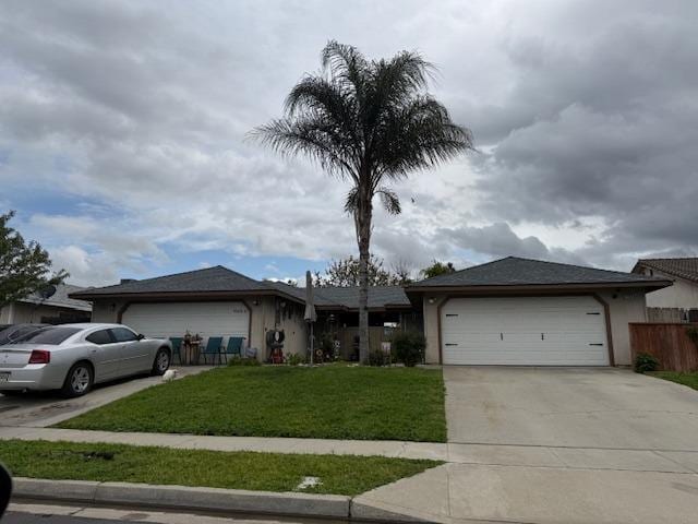 ranch-style house with a front yard, concrete driveway, a garage, and fence