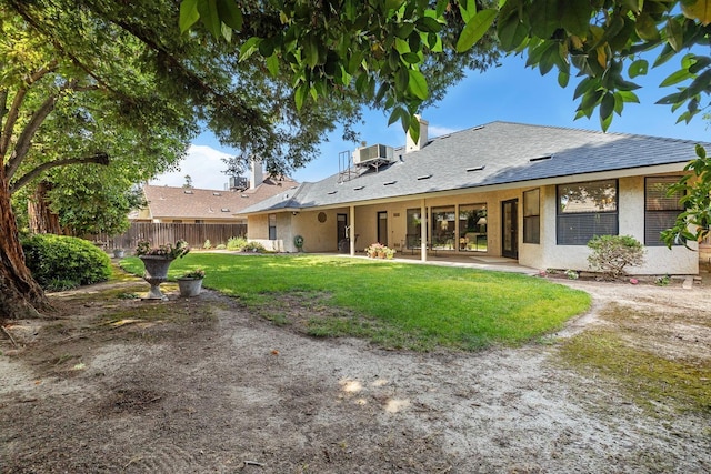 rear view of property with fence, central AC, stucco siding, a patio area, and a lawn
