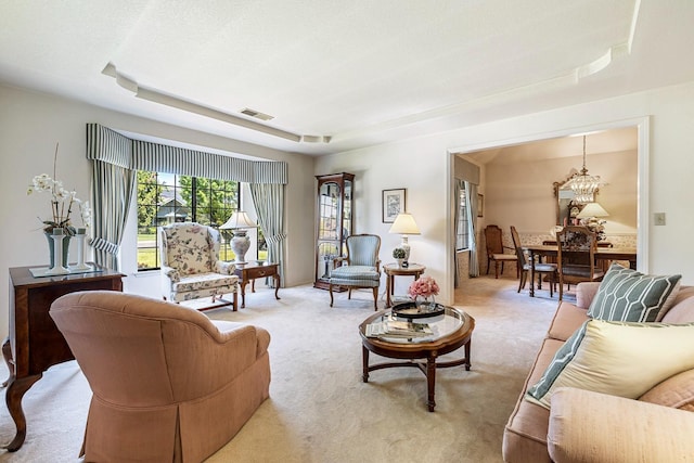 living area featuring a raised ceiling, a chandelier, light colored carpet, and visible vents