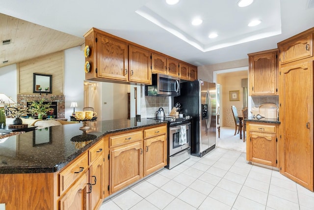 kitchen with dark stone counters, stainless steel appliances, recessed lighting, a peninsula, and tasteful backsplash