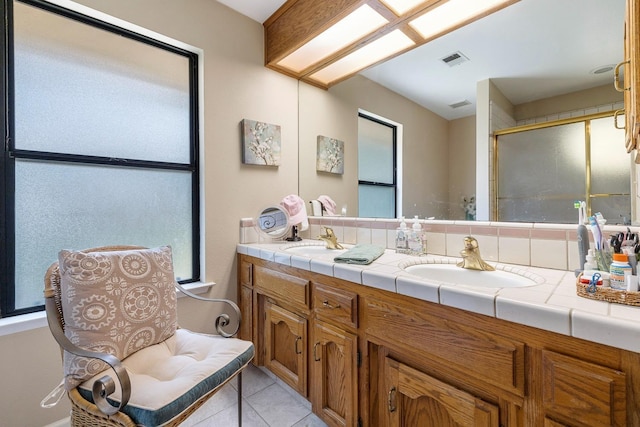 bathroom featuring a sink, tile patterned floors, a shower with door, and double vanity