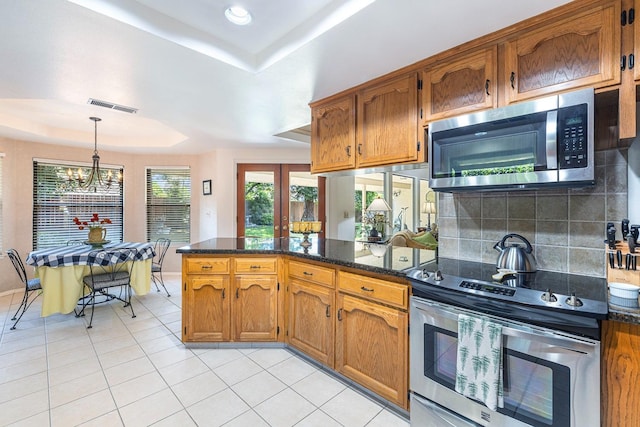 kitchen featuring brown cabinets, visible vents, appliances with stainless steel finishes, and a raised ceiling