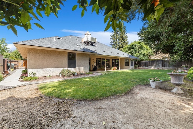 rear view of house with a yard, a fenced backyard, roof with shingles, and stucco siding
