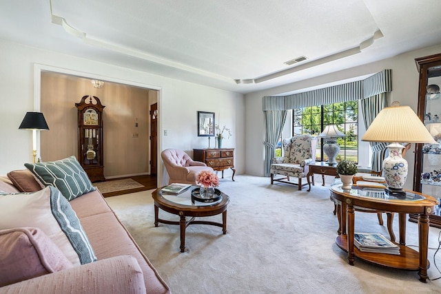 carpeted living area featuring a tray ceiling and visible vents