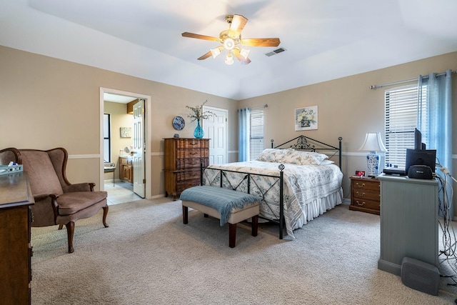 bedroom featuring ceiling fan, light carpet, ensuite bathroom, visible vents, and a closet