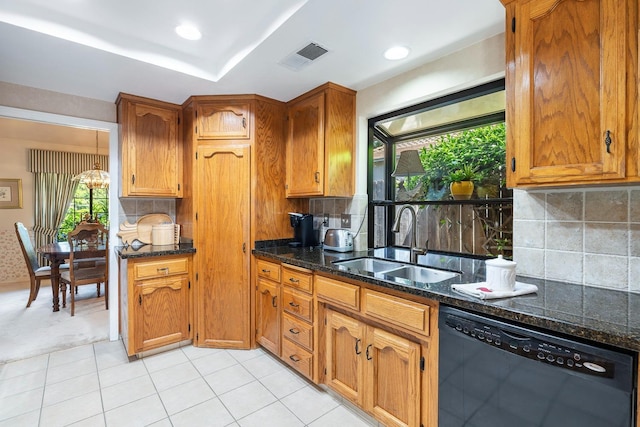 kitchen featuring backsplash, brown cabinets, dishwasher, a sink, and dark stone countertops