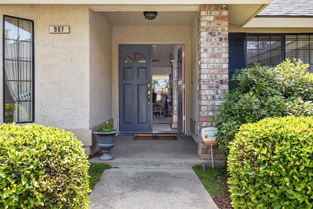 entrance to property featuring brick siding and stucco siding