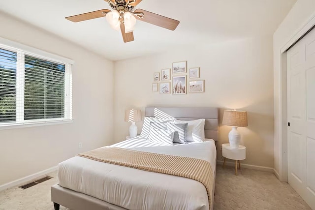 carpeted bedroom featuring a closet, visible vents, a ceiling fan, and baseboards