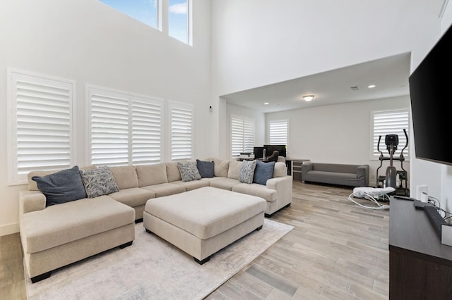 living area with a towering ceiling and light wood-type flooring