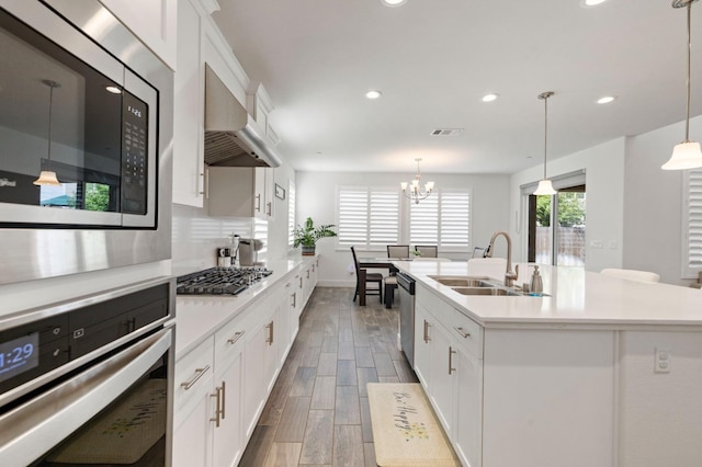 kitchen featuring recessed lighting, stainless steel appliances, light countertops, a sink, and ventilation hood