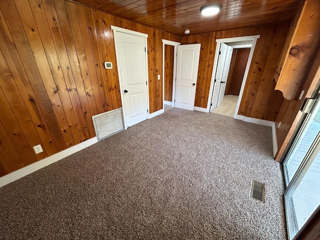 31083 Bear Paw Way, Coarsegold, CA 93614 - unfurnished bedroom featuring wooden walls, visible vents, light colored carpet, and baseboards