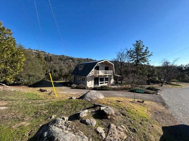31083 Bear Paw Way, Coarsegold, CA 93614 - view of home's exterior featuring a gambrel roof, a view of trees, and a balcony