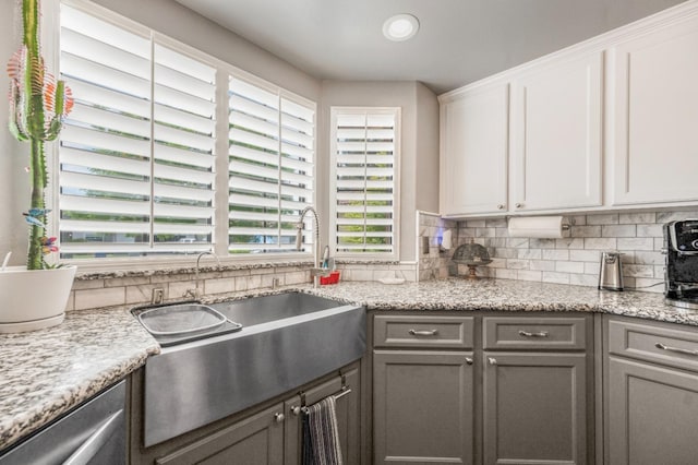 kitchen with a sink, decorative backsplash, stainless steel dishwasher, gray cabinetry, and white cabinets