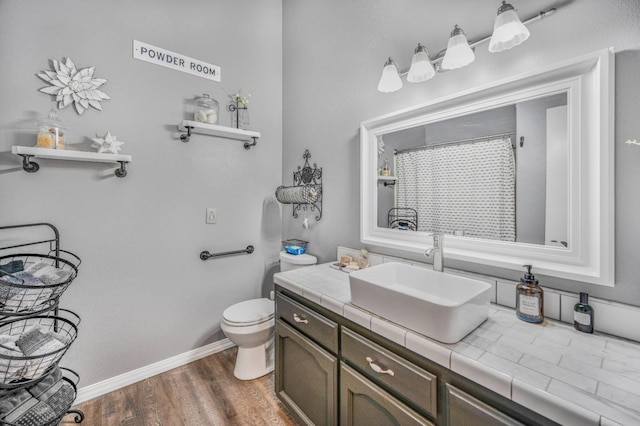 bathroom with wood finished floors, toilet, vanity, baseboards, and curtained shower