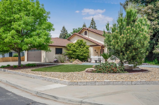 mediterranean / spanish-style home featuring fence, a tiled roof, a front yard, stucco siding, and a garage