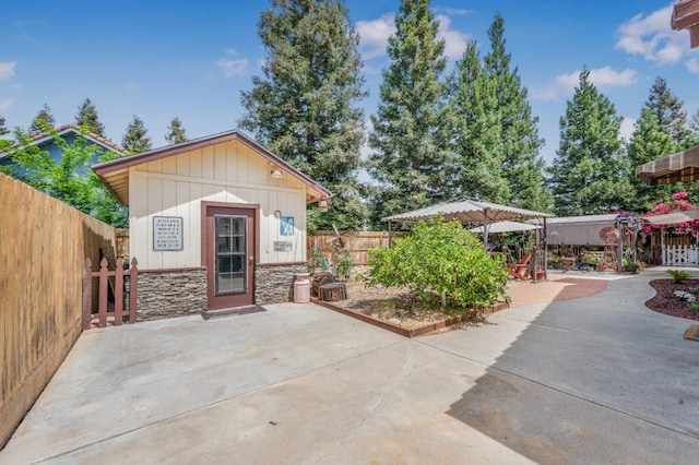 view of front of property featuring a patio, stone siding, and a fenced backyard