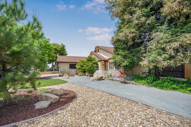 view of front of property with stucco siding, fence, and a tiled roof