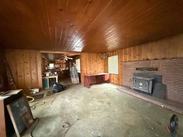 28826 Auberry Rd, Clovis, CA 93619 - unfurnished living room featuring wooden walls, a wood stove, unfinished concrete flooring, and wood ceiling