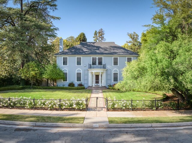 605 E Home Ave, Fresno, CA 93728 - colonial home with a fenced front yard, a gate, a balcony, a front lawn, and stucco siding