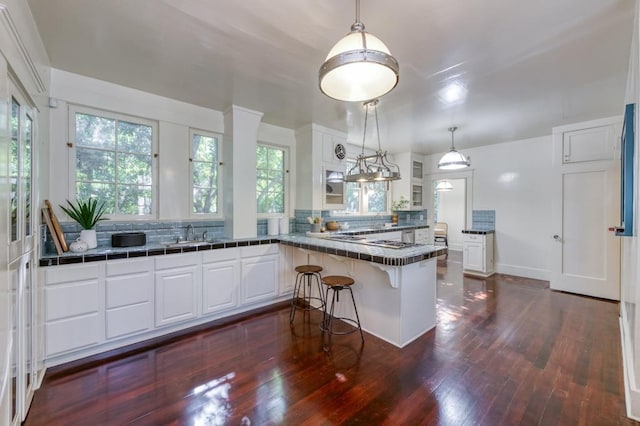 605 E Home Ave, Fresno, CA 93728 - kitchen featuring white cabinetry, a peninsula, backsplash, dark wood-style floors, and glass insert cabinets