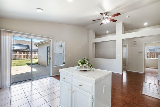 5634 W Donner Ave, Fresno, CA 93722 - kitchen with tile counters, vaulted ceiling, white cabinets, baseboards, and a ceiling fan