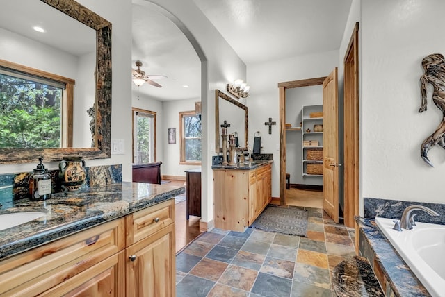 42596 Garnet Ln, Shaver Lake, CA 93664 - bathroom with stone finish flooring, two vanities, a ceiling fan, and a bath