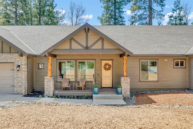 42596 Garnet Ln, Shaver Lake, CA 93664 - view of front facade featuring covered porch, roof with shingles, stone siding, and an attached garage
