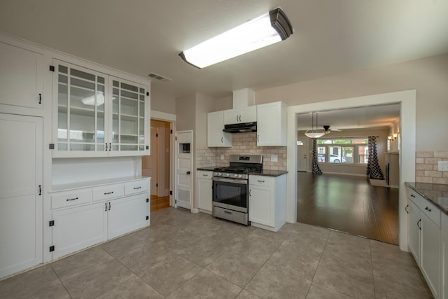 kitchen with stainless steel range with gas cooktop, decorative backsplash, white cabinets, visible vents, and under cabinet range hood