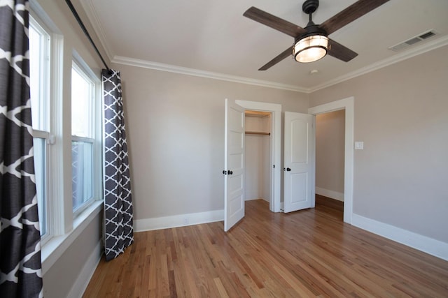 unfurnished bedroom featuring crown molding, visible vents, baseboards, light wood-type flooring, and a ceiling fan