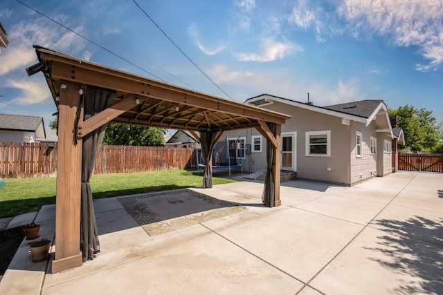 exterior space with a patio, a trampoline, a gazebo, a front lawn, and a fenced backyard