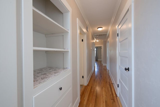 corridor featuring visible vents, light wood-style floors, and ornamental molding