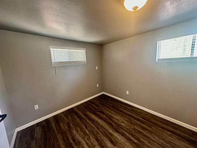 empty room featuring dark wood-style floors, baseboards, and a healthy amount of sunlight