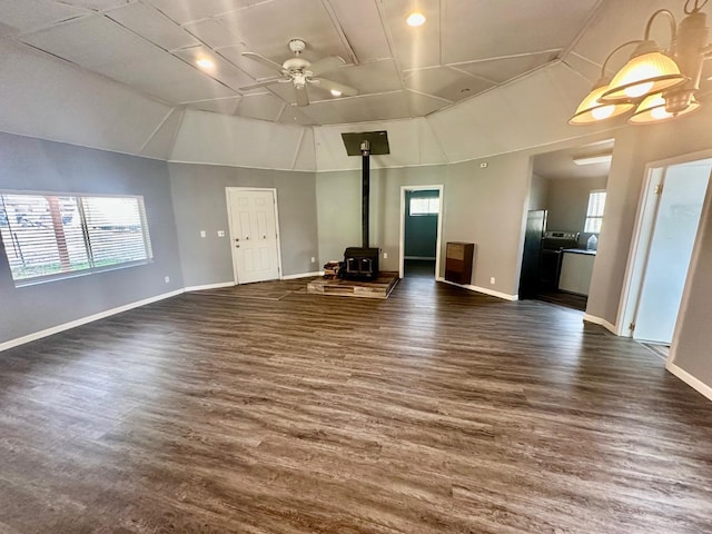 unfurnished living room with dark wood-style flooring, plenty of natural light, and a wood stove