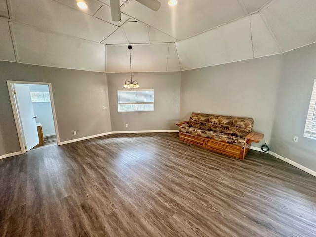unfurnished room featuring baseboards, ceiling fan with notable chandelier, vaulted ceiling, and dark wood finished floors
