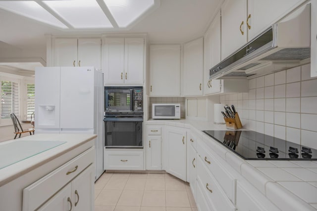 2727 W Bluff Ave Unit 136, Fresno, CA 93711 - kitchen featuring decorative backsplash, under cabinet range hood, tile counters, black appliances, and light tile patterned flooring