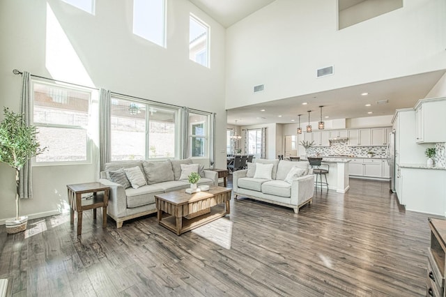 living room with visible vents, dark wood finished floors, and a high ceiling